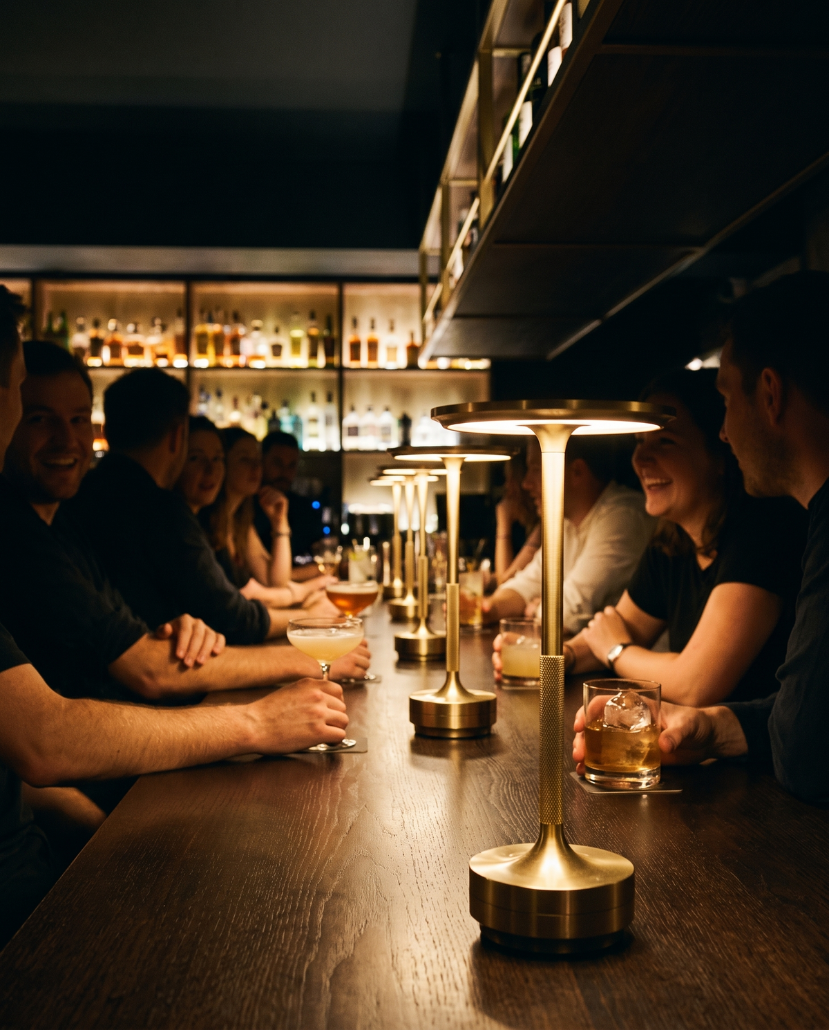Eclara Ilumina cordless lamps spaced along the counter of a busy cocktail bar in the evening