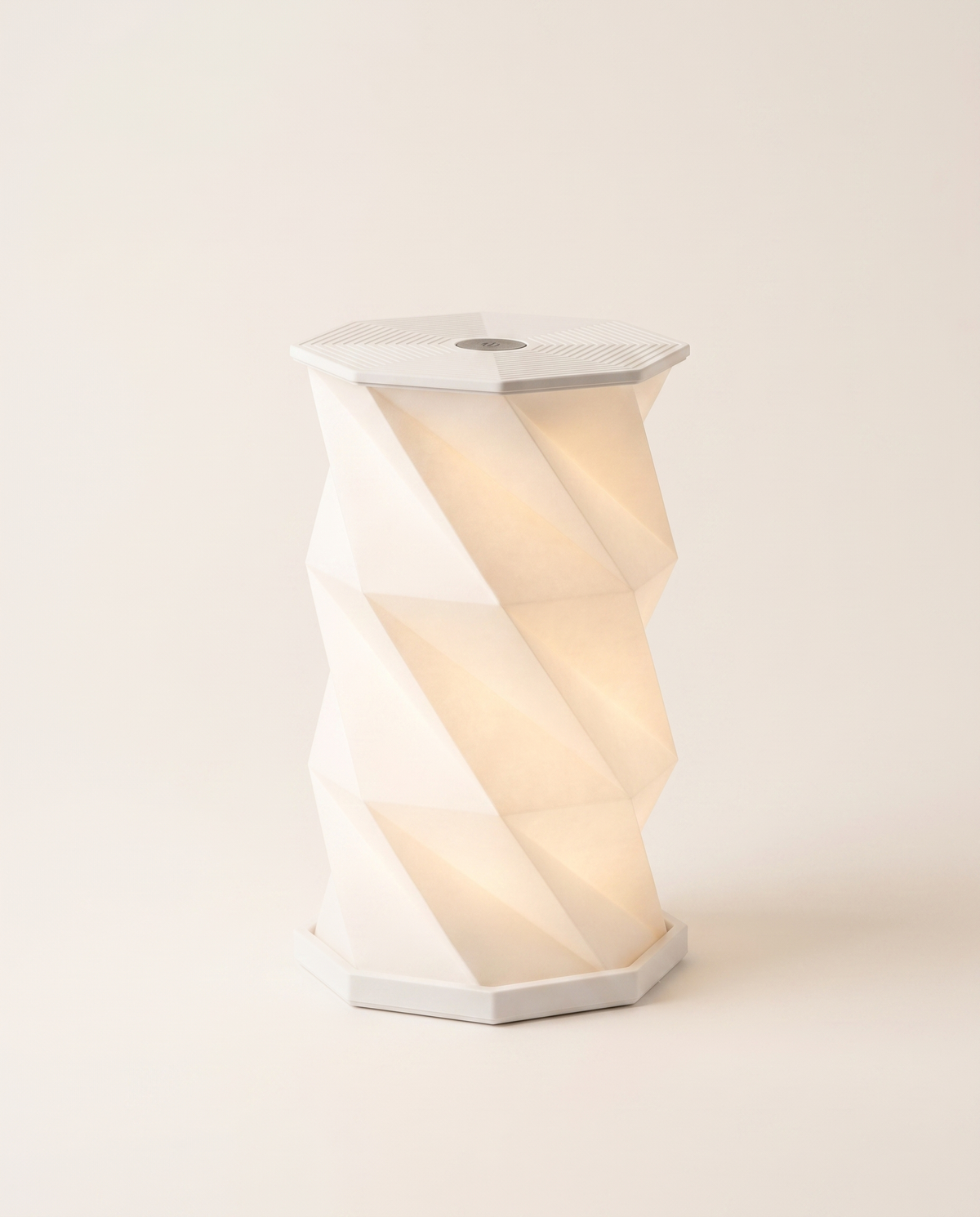 Lumina Fold origami paper table lamp lit on a neutral background