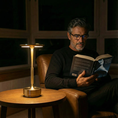 Gold Eclara Ilumina rechargeable cordless table lamp lighting a quiet reading moment in a premium living room